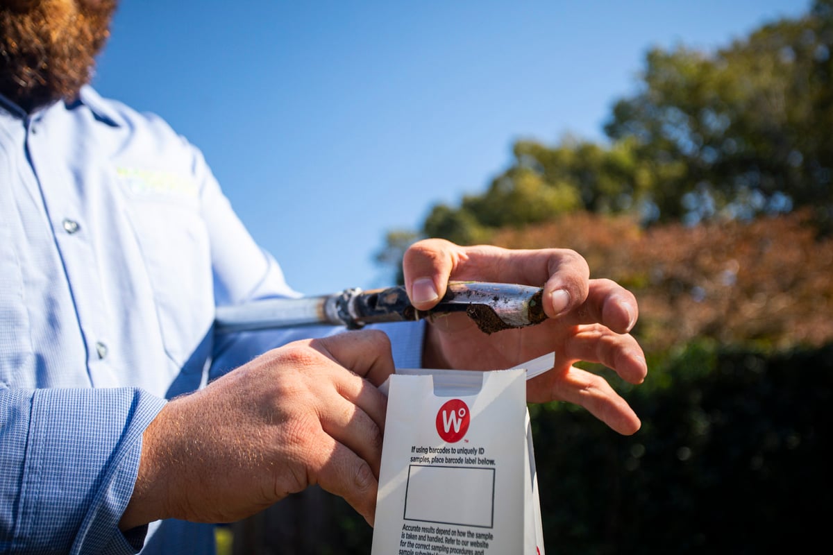 lawn care technician puts soil sample in bag