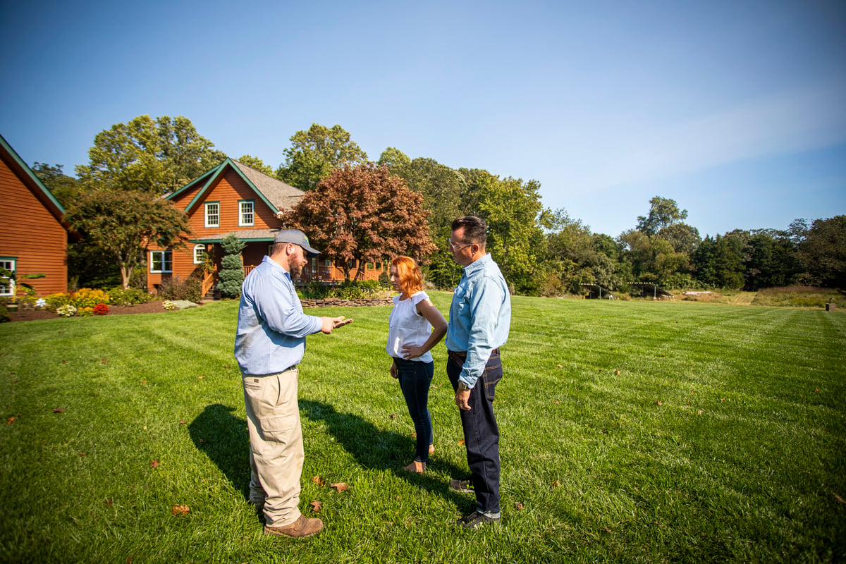lawn care expert inspects lawn with customers