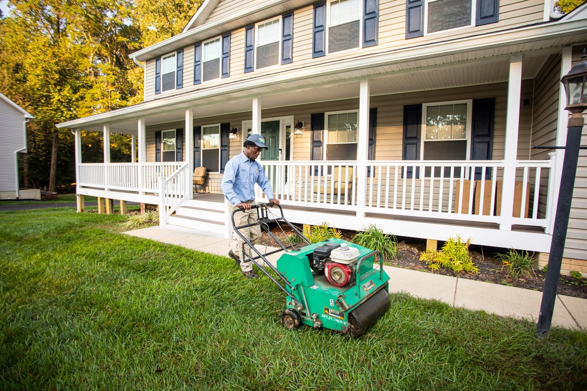 lawn care technician aerates lawn with walk behind aerator