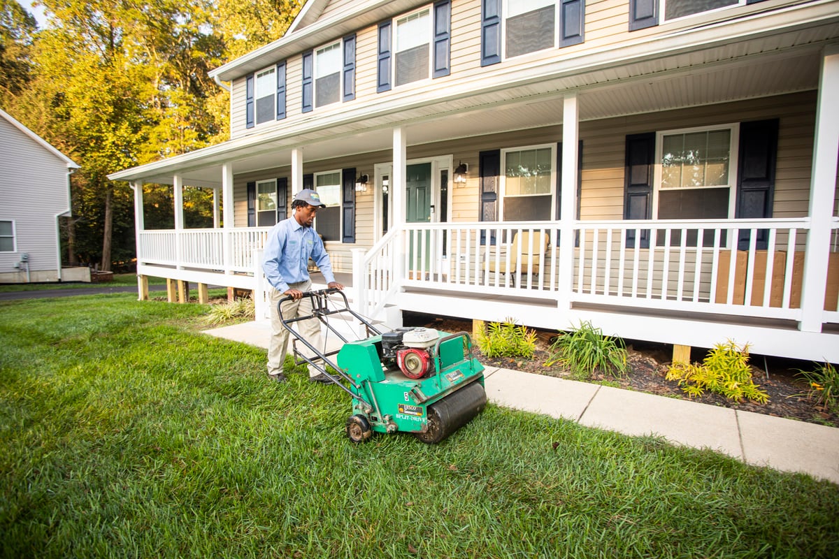 lawn care team pushes walk behind aerator at home