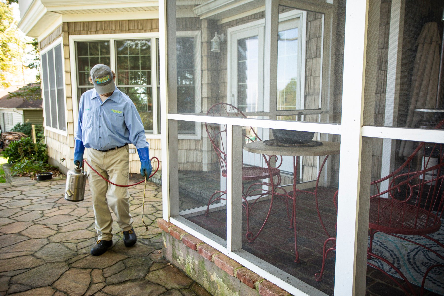 Pest control technician spraying the perimeter of the home