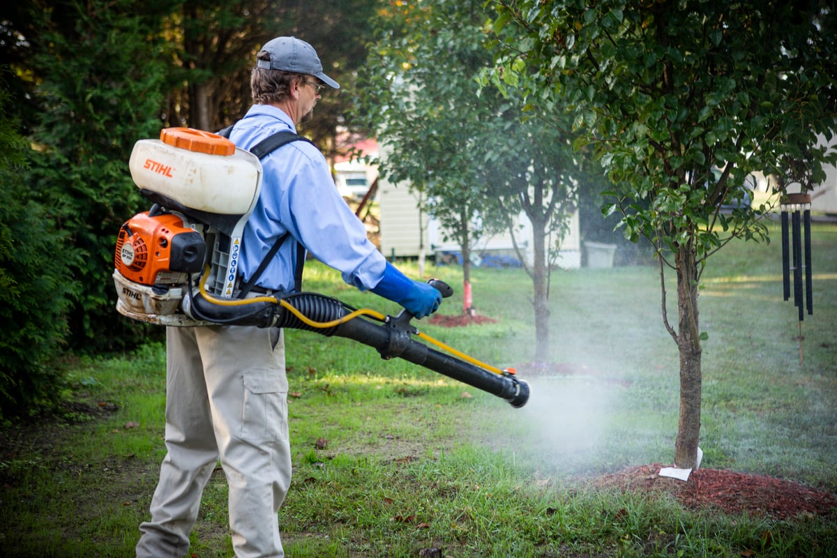 pest control technician sprays for mosquitoes