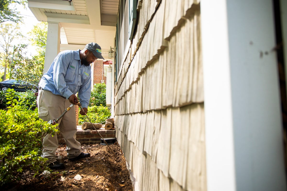 NaturalGreen technician sprays perimeter of home for pests