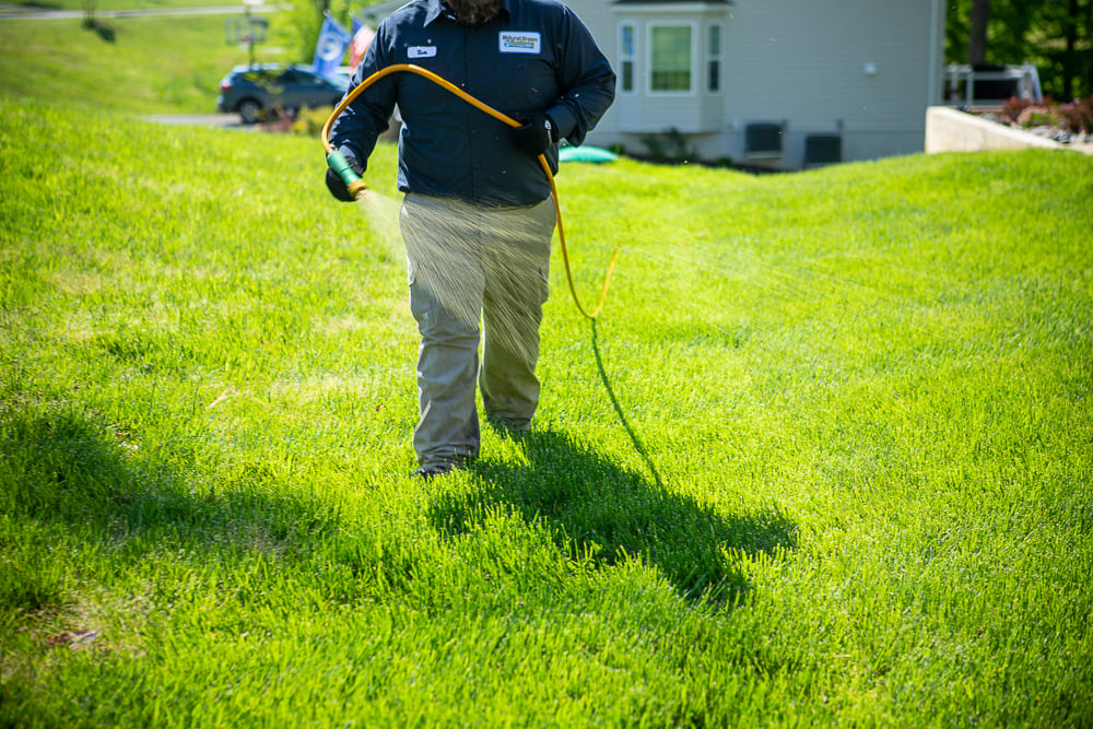 Lawn care technician spraying lawn for weeds