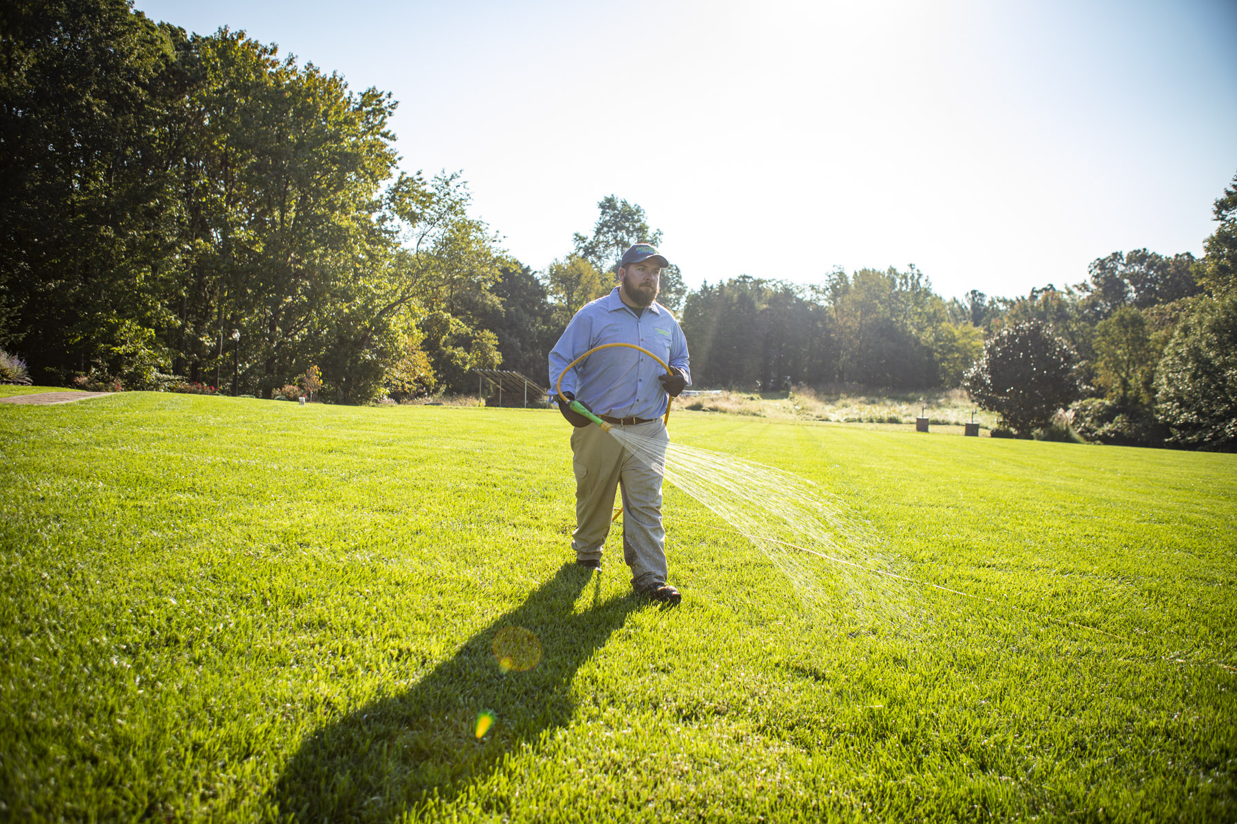 Natural Green lawn care technician spraying weed control in Maryland